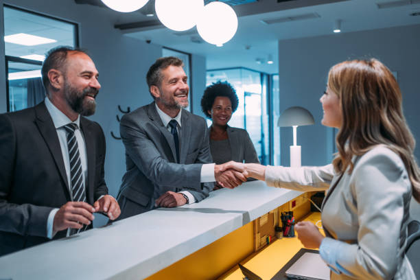 Professionals in business attire shaking hands at a reception desk, symbolizing agreements for IFZA Free Zone promotions.