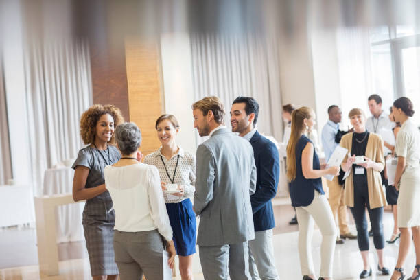 People mingling and talking in a brightly-lit conference room.