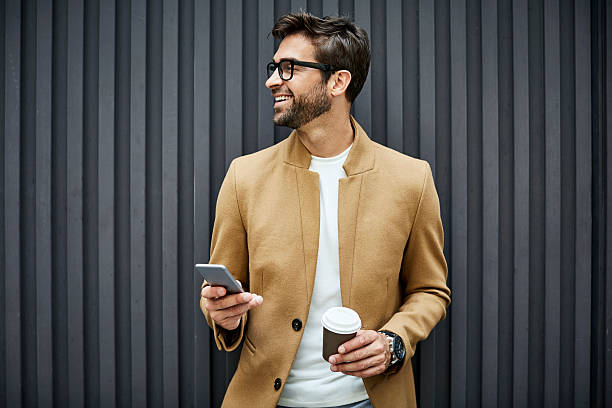 Man holding a smartphone and coffee cup while smiling, representing ease of opening a personal account in the UAE.