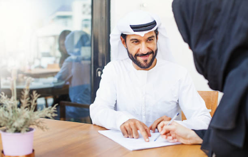 An entrepreneur in traditional attire discusses business benefits with a colleague at the IFZA Free Zone.